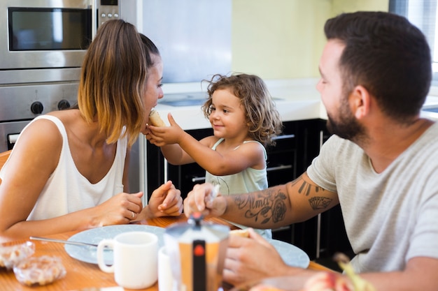 Free photo man looking at girl feeding bread to her mother