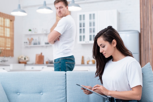 Man looking at his girlfriend that's looking on the tablet