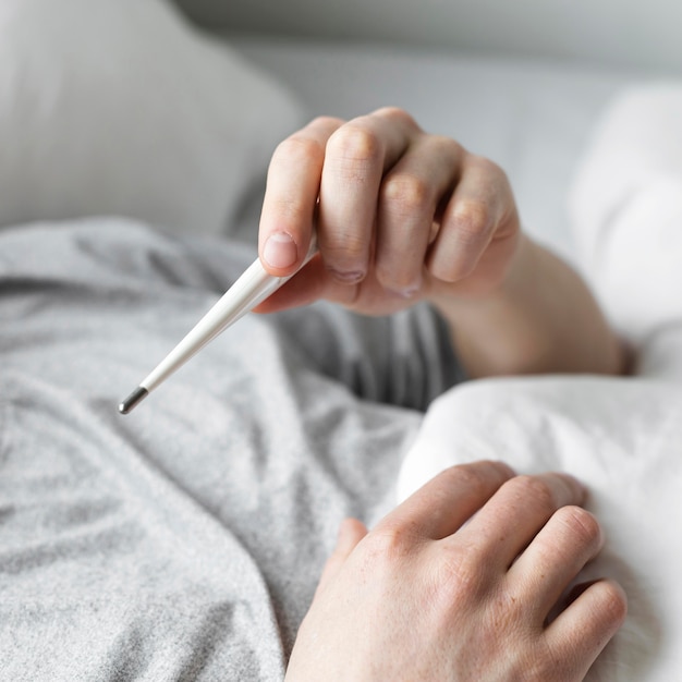 Man looking at his temperature on a thermometer