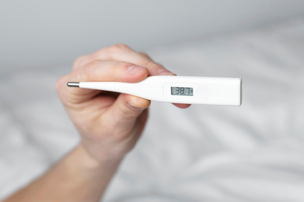 Man looking at his temperature on a thermometer