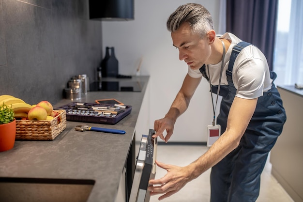 Free photo man looking at information on control panel of dishwasher