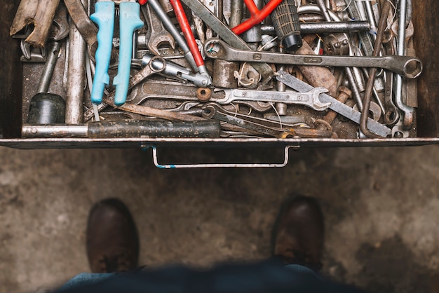 Free photo man looking into drawer full of tools