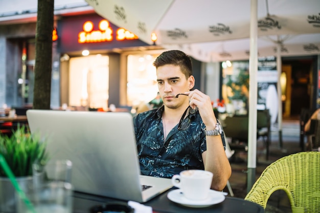 Free photo man looking at laptop screen in cafe