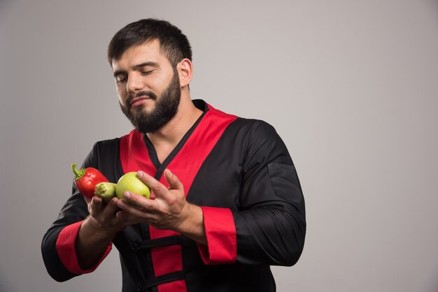 Man looking on red pepper, apple and zucchini.