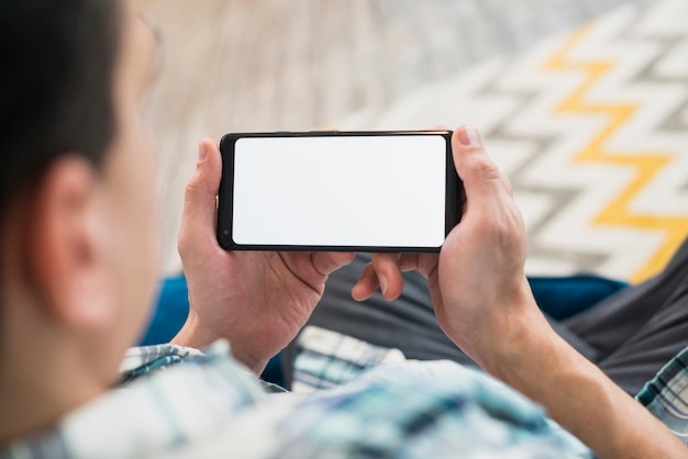 Man looking at smartphone on settee