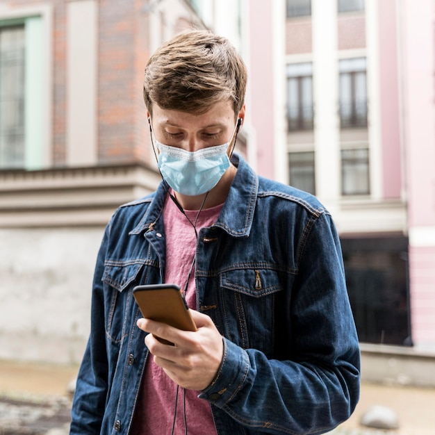 Man looking through his phone while wearing a medical mask