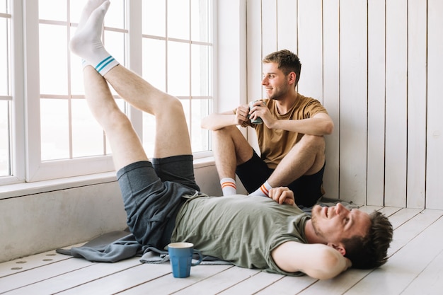 Free photo man looking through window while his friend lying on floor