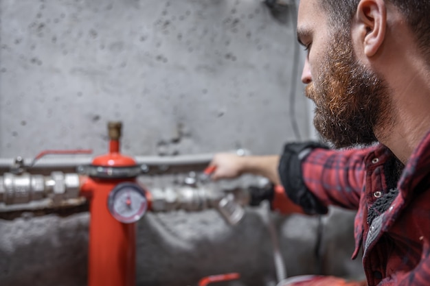 Free photo the man looks at the faucet, pipes, valve, pressure meter.