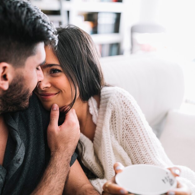 Man loving her smiling girlfriend holding cup in hand