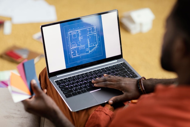 Man making plans to renovate house using color palette and laptop