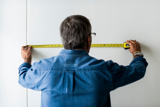 Free photo man measuring the wall with a measuring tape