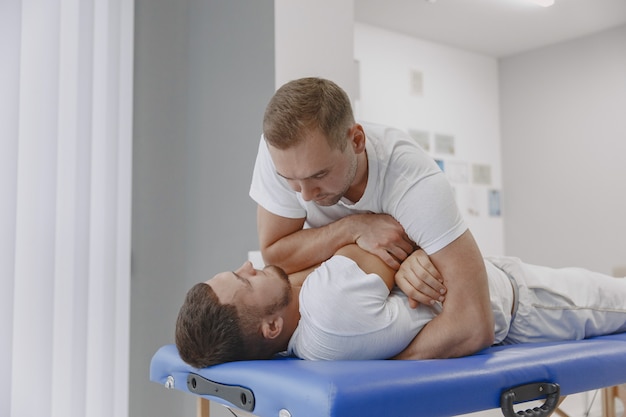 Man in the medical office. Physiotherapist is rehabilitating back.