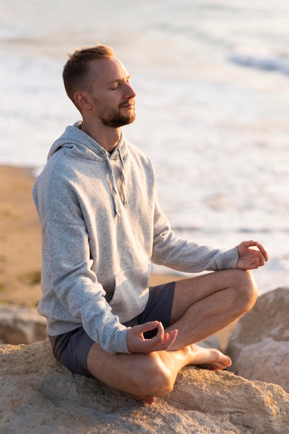 Free photo man meditating on the beach