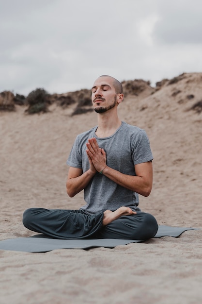 Free Photo man meditating outdoors while doing yoga