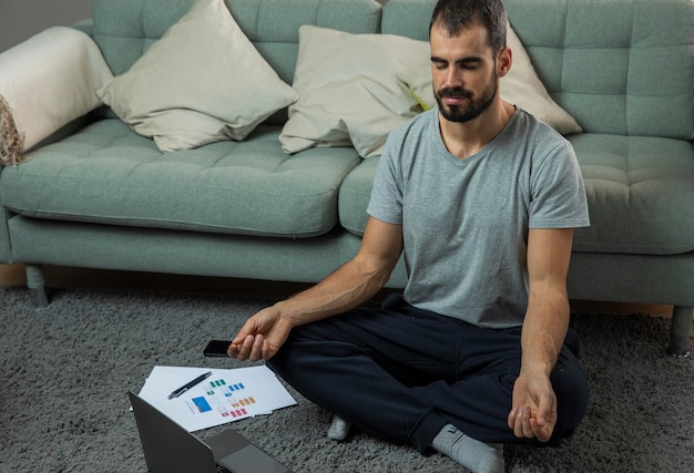 Free Photo man meditating next to sofa before starting work