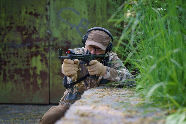 Free photo man in military ammunition stand in guard military man hide in position with weapon in hands ranger during the military operation