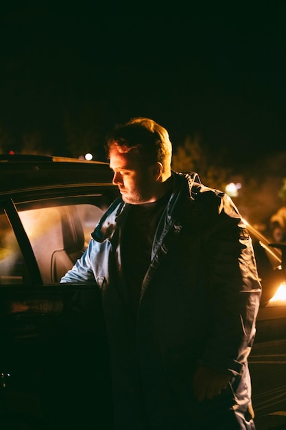 Man at night sitting next to car