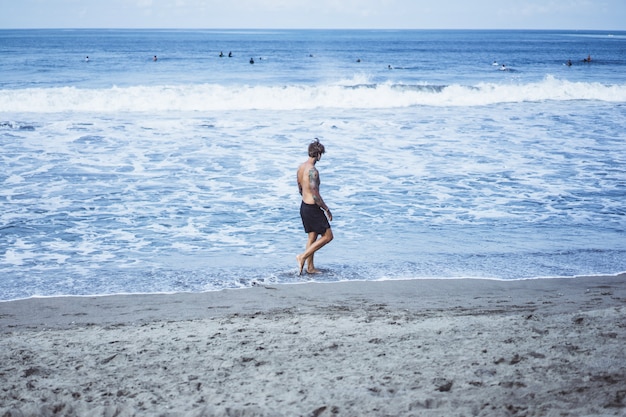 Free photo a man on the ocean coast running along the seashore