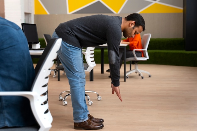 Free photo man at the office stretching during a work day