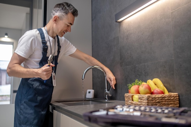 Free photo man opening faucet looking at jet of water