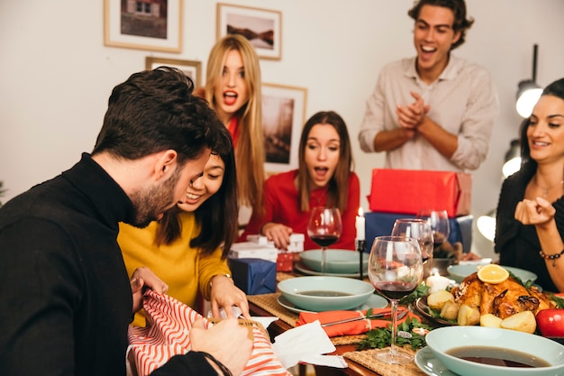 Free photo man opening gift at christmas dinner