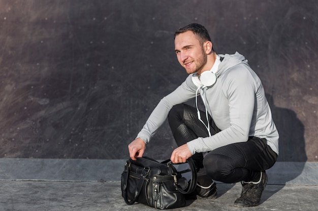 Free photo man opening a sport bag and looking away