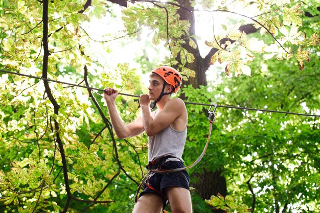 Man in an orange helmet is ready to climb the rope