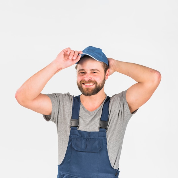 Man in overall putting cap on head