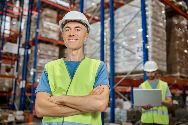 Man in overalls looking at camera and colleague behind