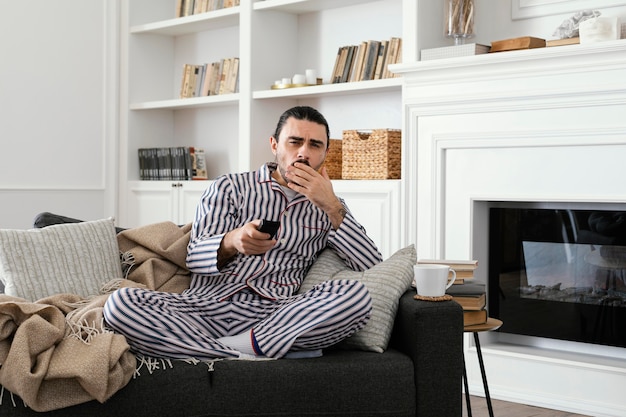 Free photo man in pajamas watching tv  front view