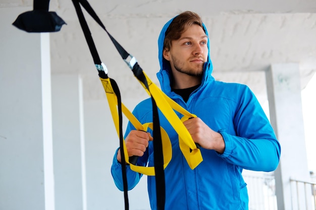 Free photo a man in a park improving his legs flexibility with fitness trx strips.