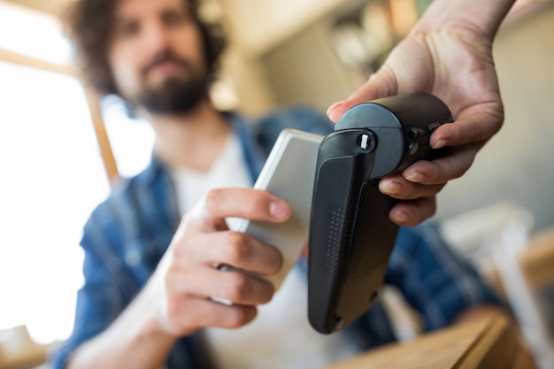 Man paying with NFC technology on mobile phone