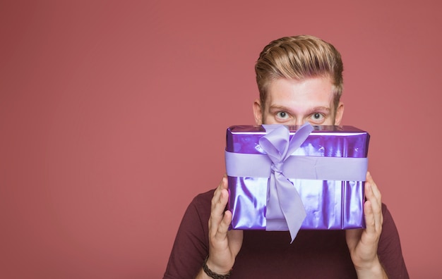 Free photo man peeking from wrapped gift box with decorative bow