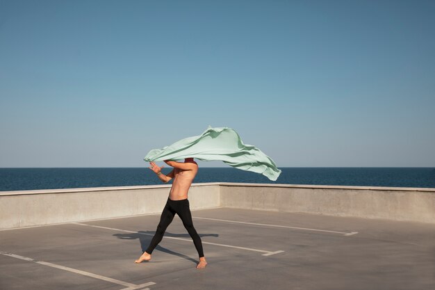 Man performing artistic dance on a rooftop with blue sky