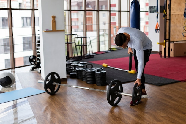 Free photo man placing weight plates on bar