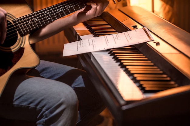 man playing acoustic guitar and piano close-up