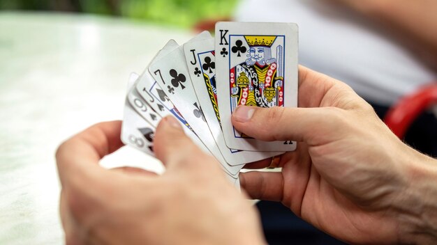 A man playing cards with other people holding a deck