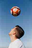 Free photo man playing football at the beach