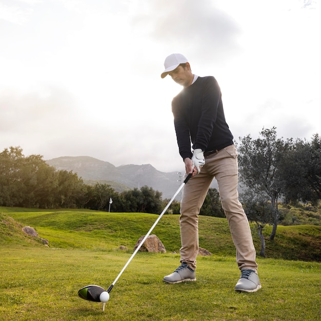 Free photo man playing golf on the field with club