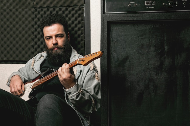 Man playing guitar next to amplifier