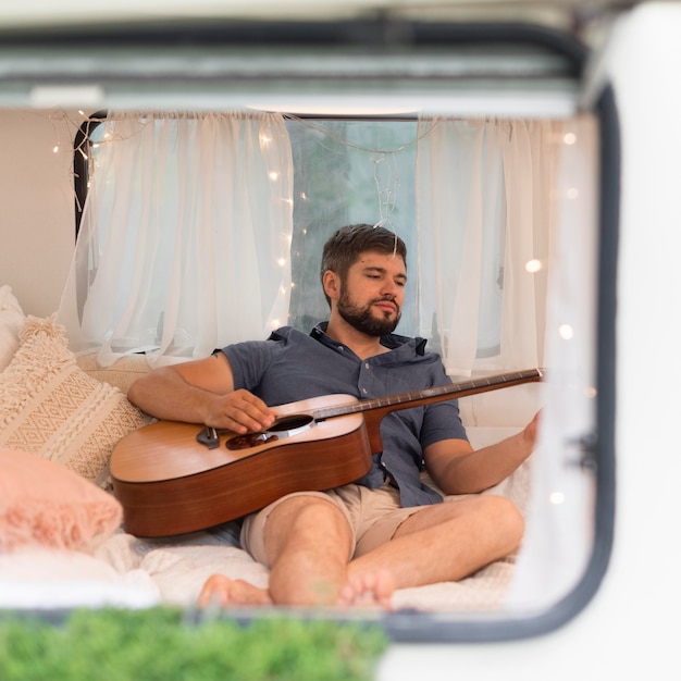 Free photo man playing the guitar in a caravan