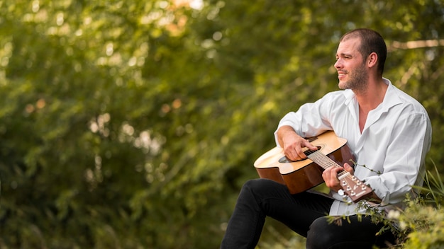 Free Photo man playing the guitar in the nature copy space