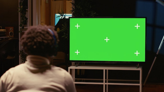 Free photo man playing singleplayer videogames on green screen tv in cozy living room