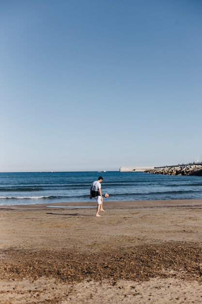 Man playing with football at the beach