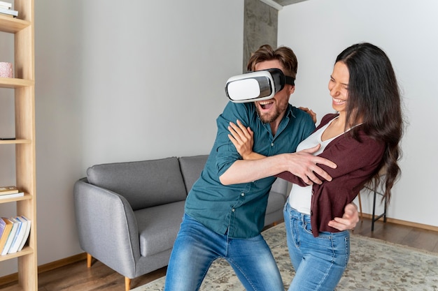 Free photo man playing with virtual reality headset at home next to woman