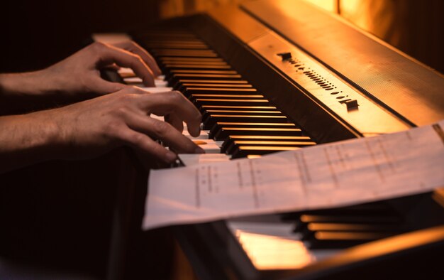 man plays the notes on the piano, close-up, beautiful color background, the concept of musical activity