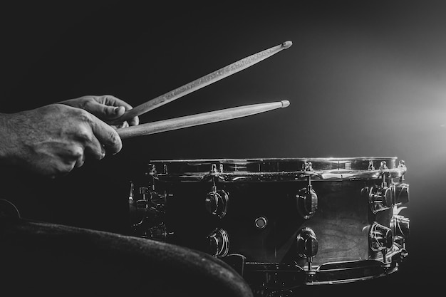 A man plays with sticks on a drum, a drummer plays a percussion instrument, copy space, monochrome.