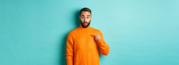 Free photo man pointing at himself with surprise face being chosen standing confused against light blue backgro