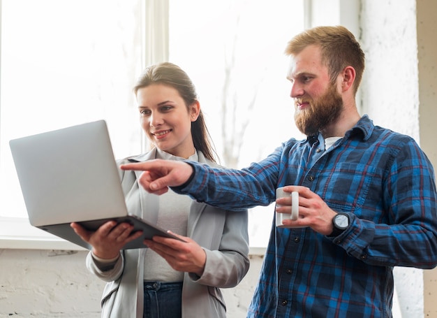 Free Photo man pointing at laptop hold by his female colleague