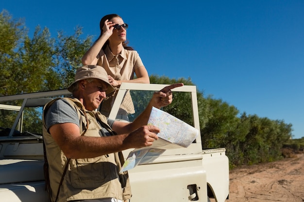 Free photo man pointing while holding map with woman in vehicle